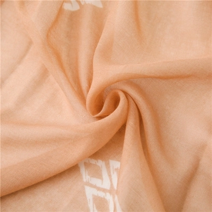 Macro shot of apricot fabric with white geometric patterns and light translucent texture