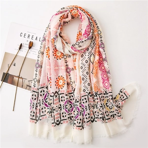 Close-up of ivory cotton linen scarf with colorful floral patterns and fringe edges