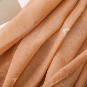Detailed macro view of light brown cotton scarf featuring white star patterns and fabric texture