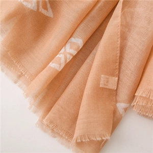 Close-up of lightweight light orange viscose scarf showing fine fabric texture and fringe edges