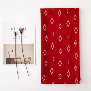 Flat lay of a red long scarf with white geometric patterns beside a Cereal magazine