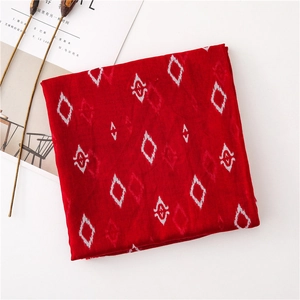 Flat lay of red geometric diamond scarf with dried flowers on a white surface