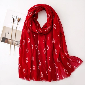 Detailed view of red bohemian cotton scarf with white diamond patterns and frayed edges
