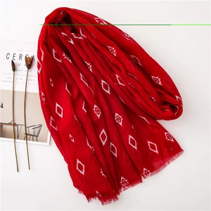 Flat lay of red geometric pattern scarf with fringe edges and cereal magazine decor