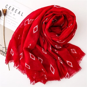 Macro detail of red cotton scarf with white geometric patterns and frayed edges