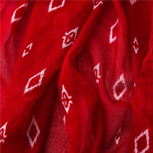 Macro detail of red cotton scarf fabric featuring white diamond patterns and woven texture