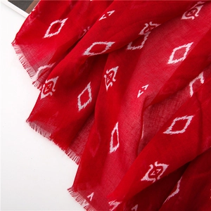 Close-up of red scarf showing geometric diamond pattern and raw frayed edges texture