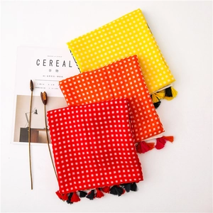 Three-piece checkered scarf set with fringes in yellow, orange, and red over magazines