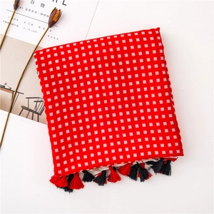 Macro detail of red and white checkered knit scarf featuring red and black fringe accents