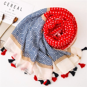 Detailed view of red and blue geometric printed scarf with handcrafted tassels and fringe