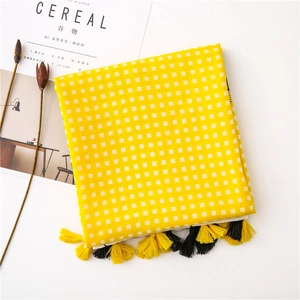 Close-up of yellow and white checkered tablecloth with decorative fringe tassels