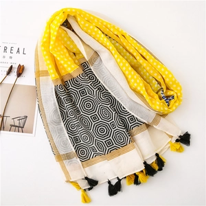 Detail of yellow and beige patchwork scarf with geometric patterns and fringe tassels