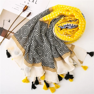 Detailed view of yellow plaid and geometric hexagon patterns on a soft fringed scarf