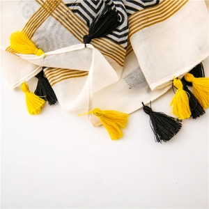 Close-up of geometric pattern scarf with long yellow and black tassels fringe details