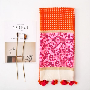 Flat lay of a lightweight rectangular scarf with geometric patterns and orange tassels