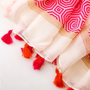 Detail of white scarf featuring pink geometric octagons and vibrant colored fringe tassels