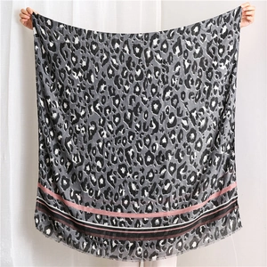 Detail view of leopard print scarf with striped border and delicate fringe edges