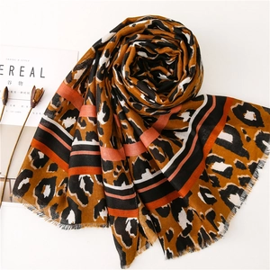 Detail of leopard print scarf with orange stripes and delicate fringe on white background