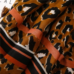 Close-up of leopard print scarf with orange striped border and soft fabric texture