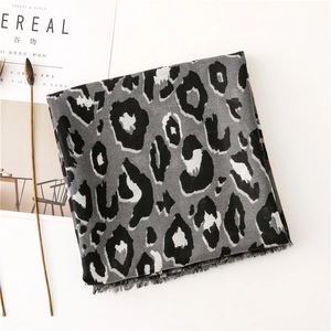Detailed view of grey leopard print scarf with fringed edges on a white background
