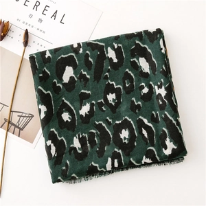 Detail of dark green leopard print scarf featuring tassel edges and soft woven texture