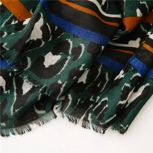 Detail of leopard and stripe print scarf showing dark green fabric texture and fringe edges
