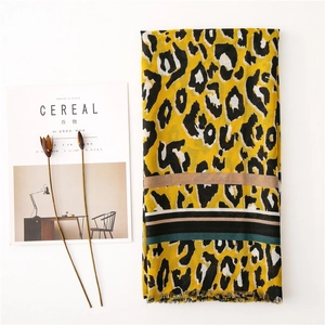 Detail of yellow leopard print scarf with multicolor stripes and frayed edges on white background