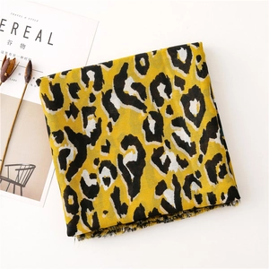 Detail of yellow leopard print scarf with fringe edges on a minimalist white background