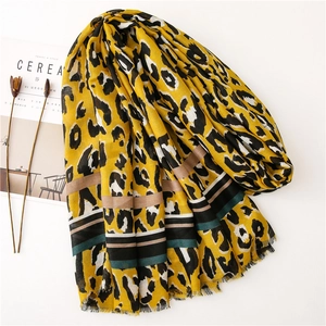 Detail shot of yellow leopard print scarf with striped borders and delicate tassels