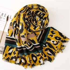 Detail of leopard print scarf with colorful stripes and frayed edges on a white surface