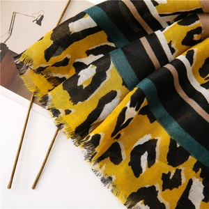 Detail of leopard print scarf featuring vibrant yellow patterns and fringed edges