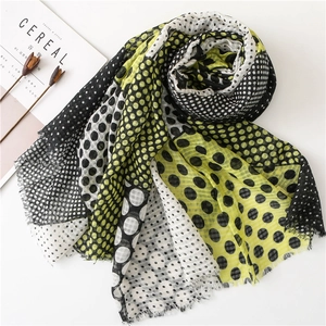 Classic yellow and black polka dot scarf with frayed edges on a minimalist background