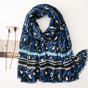 Blue leopard print scarf with striped borders and fringe ends on a minimalist white backdrop