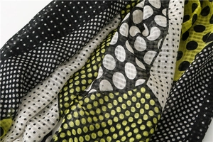 Detailed macro view of woven fabric texture and polka dot print on the lightweight scarf