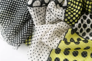 Detailed close-up of a plaid scarf fabric showing frayed edges and soft dot patterns
