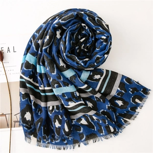 Detailed macro view of leopard print cotton scarf with fringed edges and soft blue tones