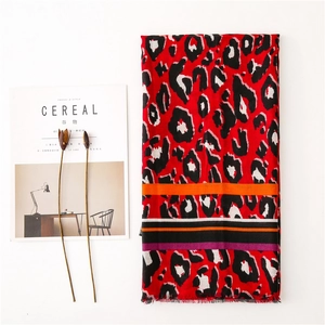Close-up of red leopard print scarf with colorful striped edges and delicate tassel fringe