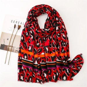 Detail of red leopard print scarf with striped hem and soft fringe texture on white background