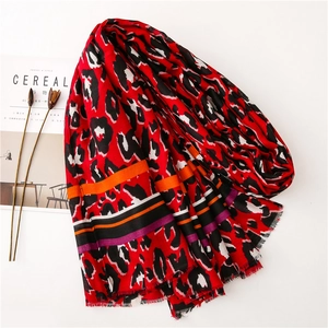 Detail shot of leopard print scarf with red patterns, soft fringe edges and striped hem
