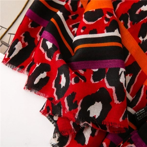 Close-up of vibrant red leopard print scarf with striped details and delicate fringes