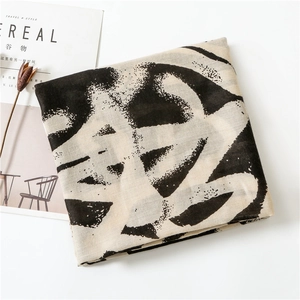 Close-up of beige cotton linen scarf with black graffiti print and fine fabric texture