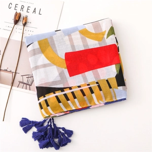 Detailed flat lay of a colorful geometric scarf with fringe and a minimalist aesthetic