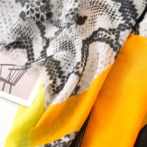 Detail of snake skin print scarf with orange color block and frayed edge textures