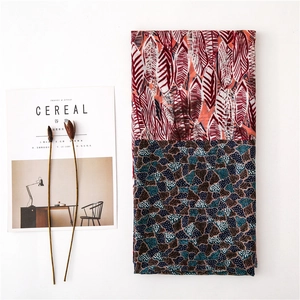 Elegant scarf with red feather patterns and mosaic stone print against a clean white backdrop