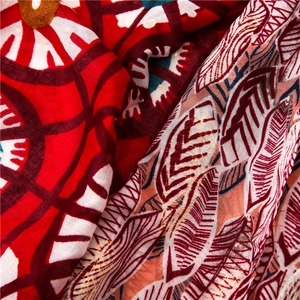 Detail of bohemian scarf fabric with red geometric patterns and gold feather leaf prints