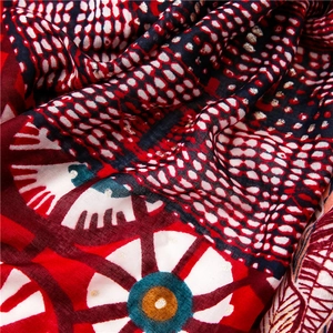Macro detail of red cotton scarf featuring gold foil feathers and geometric patterns