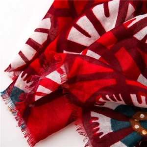 Detail of red cotton linen scarf showing gold foil feathers and delicate fringe edges