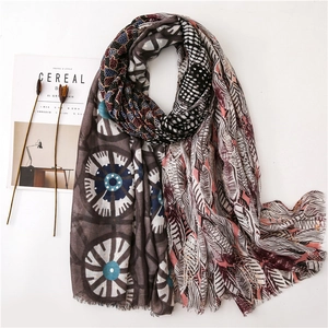 Detailed top view of a gold-stamped feather pattern scarf with frayed edges