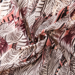 Detail of elegant scarf fabric with golden feather embroidery and tropical leaf patterns