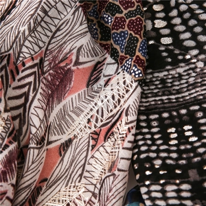 Macro view of cotton linen shawl with gold foil feather pattern and sequin embroidery details